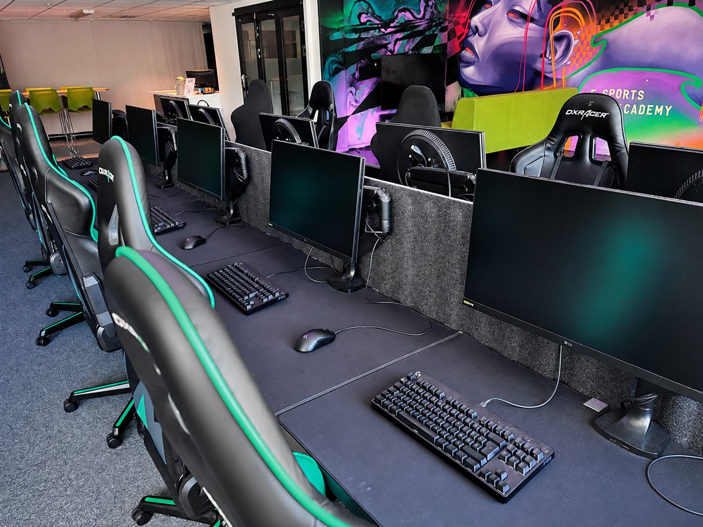Gamingplatser med datorer, tangentbord och headset i E-Sports Academys gamingcenter