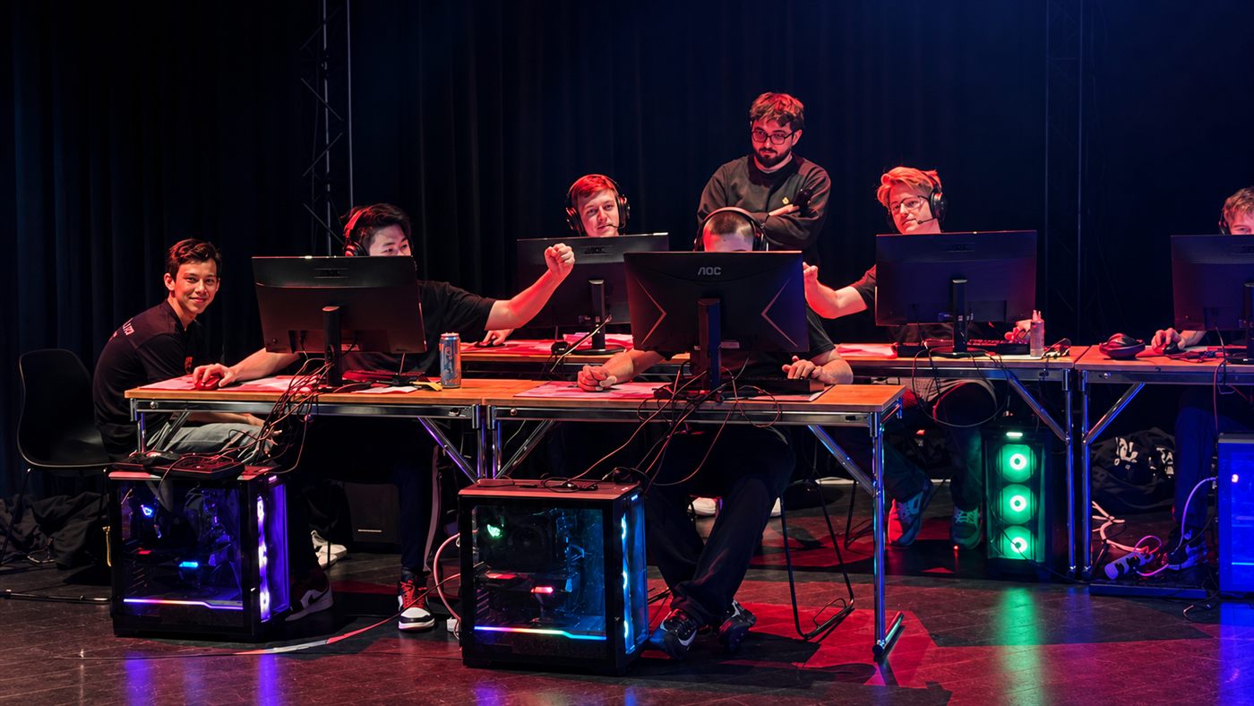 E-sportlag spelar tillsammans vid datorer på scen